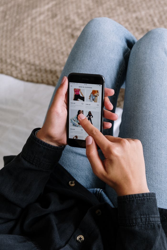 Close-up of a woman shopping online on a smartphone while relaxing at home.